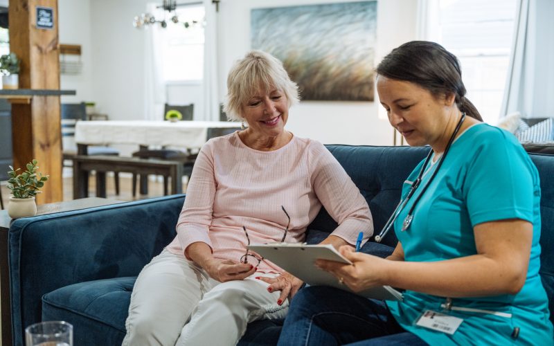 Doctor visiting senior woman at home, doing medical exams and checking health