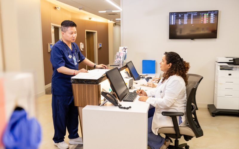 While working to update electronic medical records, the female doctor looks up to talk with her colleague.